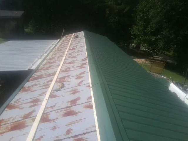 Old rusted panels beside newly installed green metal roofing — Wind Damage Roof Repair by Roofing Brothers in Mascotte