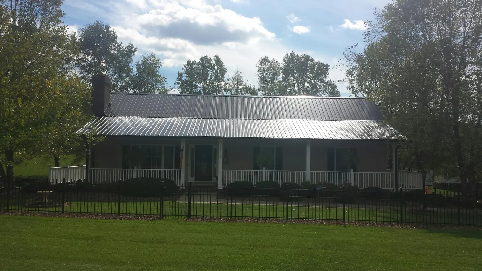 Gray metal roof on a brick ranch with a full width front porch — Gutter Guard Installation work by our crew in Mascotte