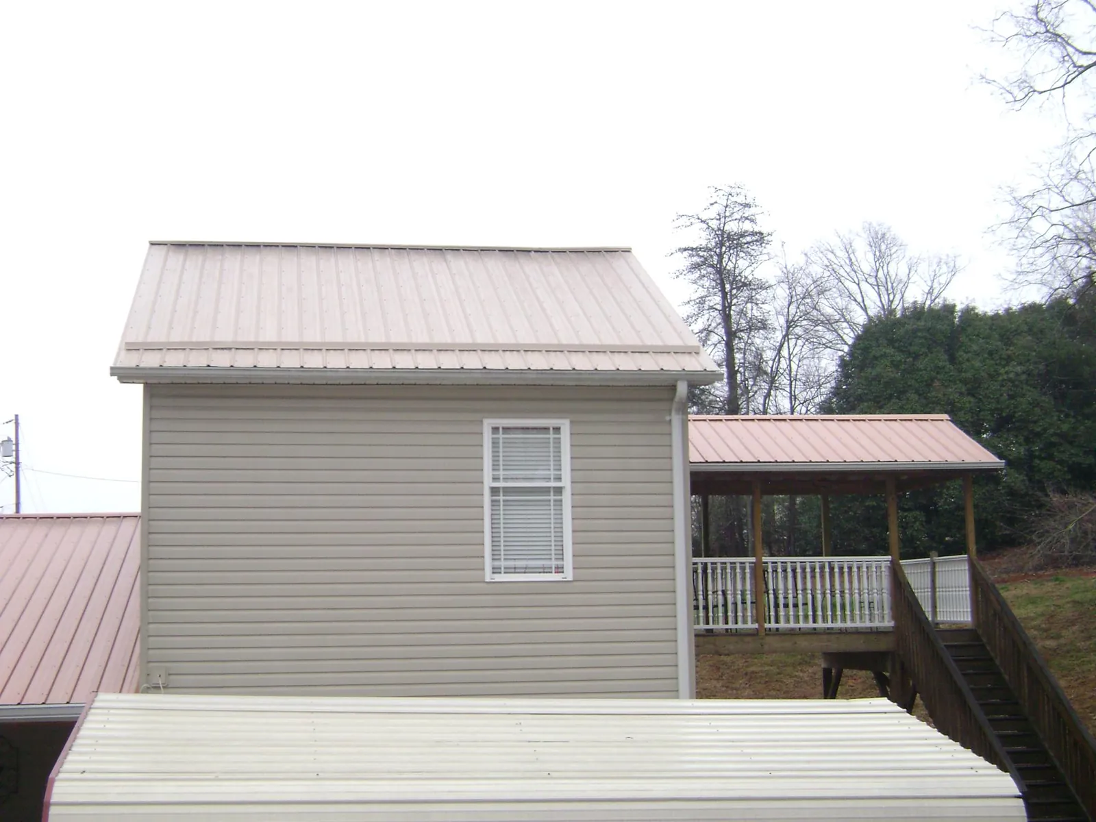 Tan metal roofs on a two story addition and attached porch, from a Roof Replacement job in Mascotte