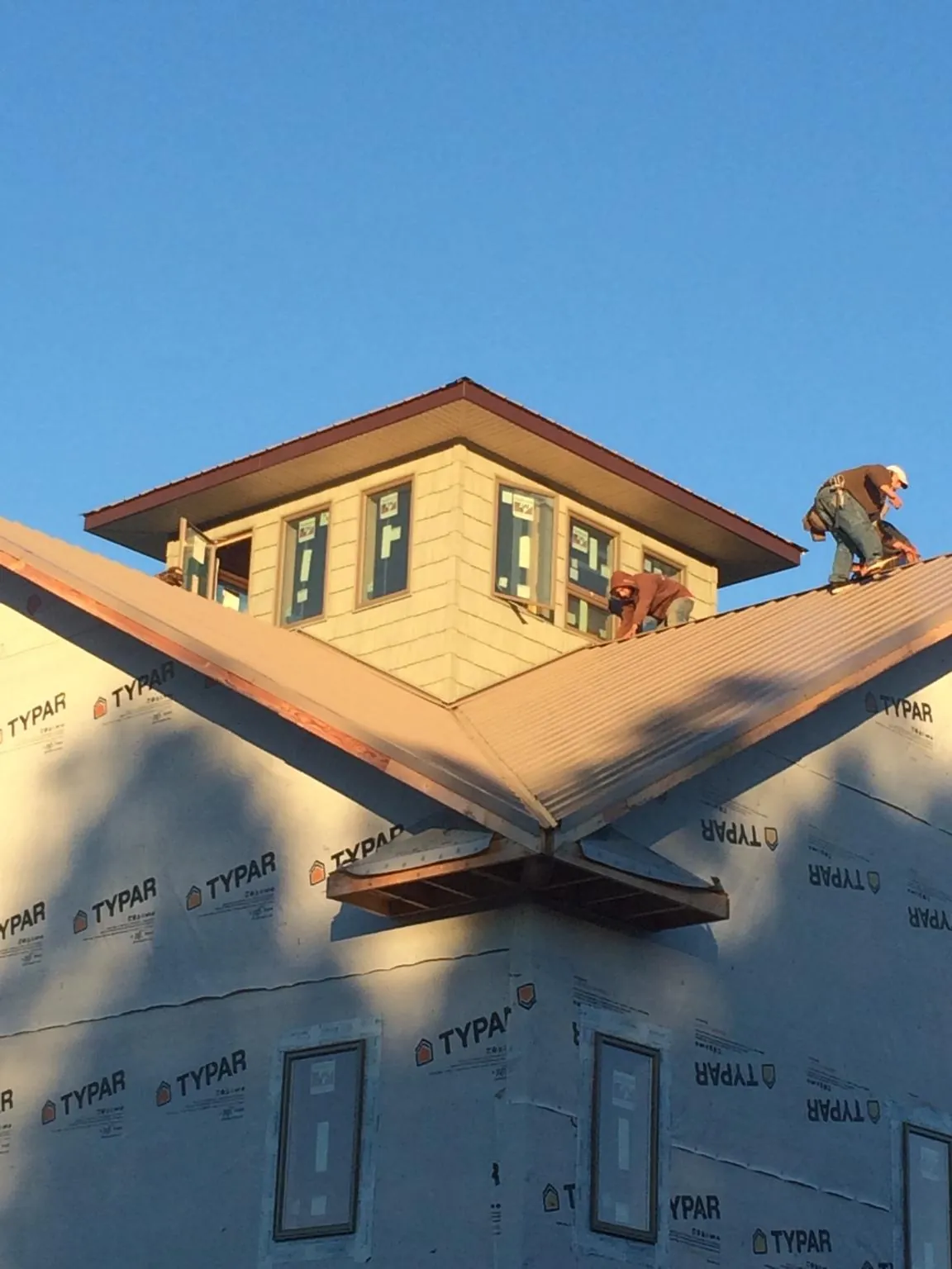 Roofers working around a rooftop cupola on a new metal roof at sunset — Roof Waterproofing in Mascotte by Roofing Brothers